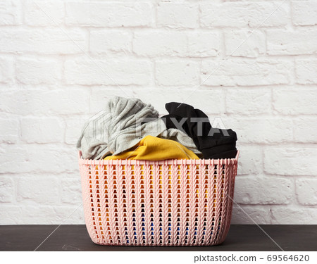 full pink plastic round laundry basket with white brick wall background full pink plastic round laundry basket with white brick wall background 69564620