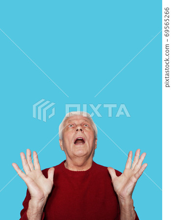 Elderly man with expression of amazement on blue background Elderly man with expression of amazement on blue background 69565266