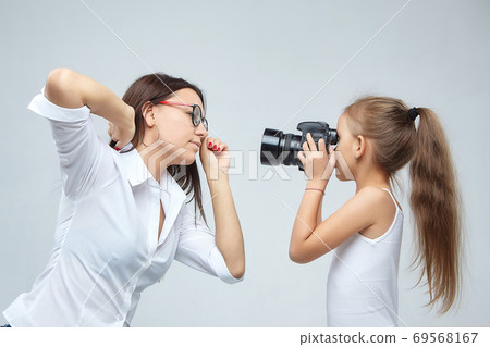 little girl with glasses, lying in the Studio with a camera little girl with glasses, lying in the Studio with a camera 69568167