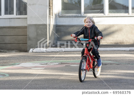 Boy is biking on the paved area. Child learns to ride bike Boy is biking on the paved area. Child learns to ride bike 69568376
