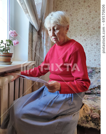Woman holding cash in front of heating radiator. Payment for heating in winter. Selective focus. 69570606