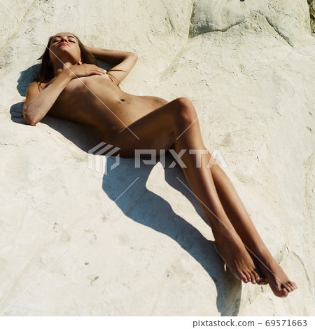 Beautiful nude woman on the beach with white stone 69571663