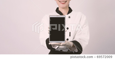 Middle aged of asian woman chef holding smartphone or digital tablet received order from online shop Middle aged of asian woman chef holding smartphone or digital tablet received order from online shop 69572009