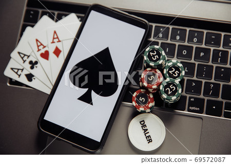 Online poker casino theme. Gambling chips, smartphone and playing cards on laptop keyboard Online poker casino theme. Gambling chips, smartphone and playing cards on laptop keyboard 69572087