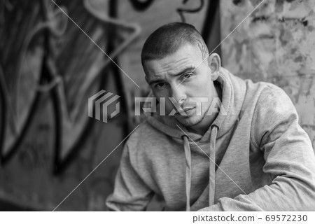 A bully guy in a light sports jacket with a hood. Black and white photo. BW A bully guy in a light sports jacket with a hood. Black and white photo. BW 69572230