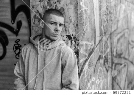 A bully guy in a light sports jacket with a hood. Black and white photo. BW A bully guy in a light sports jacket with a hood. Black and white photo. BW 69572231