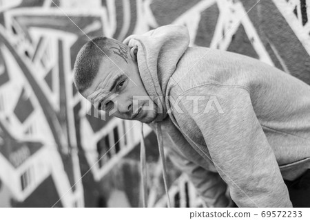 A bully guy in a light sports jacket with a hood. Black and white photo. BW A bully guy in a light sports jacket with a hood. Black and white photo. BW 69572233