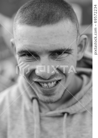 A bully guy in a light sports jacket with a hood. Black and white photo. BW A bully guy in a light sports jacket with a hood. Black and white photo. BW 69572234