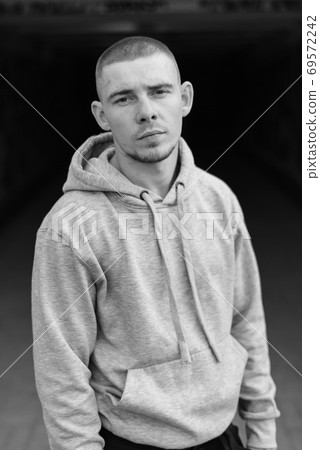 A bully guy in a light sports jacket with a hood. Black and white photo. BW 69572242