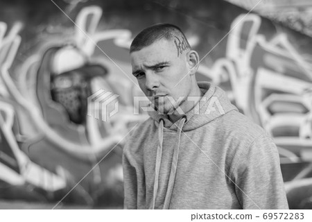 A bully guy in a light sports jacket with a hood. Black and white photo. BW A bully guy in a light sports jacket with a hood. Black and white photo. BW 69572283