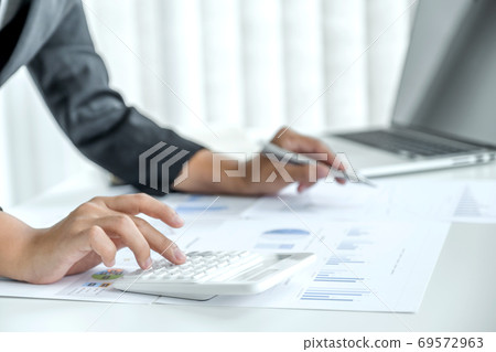 businesswomen bookkeeper use calculator and laptop doing account for paying tax on white desk businesswomen bookkeeper use calculator and laptop doing account for paying tax on white desk 69572963