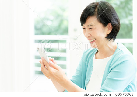 打在她的智能手機上的視頻通話的中年女人 打在她的智能手機上的視頻通話的中年女人 69576365