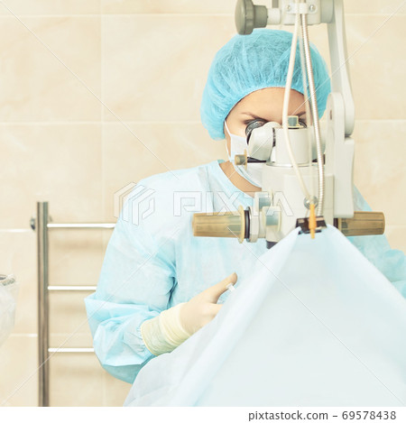 Pretty doctor woman portrait. Ophthalmology laser microscope operation. Clinic room. Patient eye treatment. Myopia and cataract removal 69578438