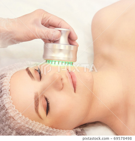 Light infrared therapy. Cosmetology head procedure. Beauty woman face. Cosmetic salon device. Facial skin rejuvenation 69578498