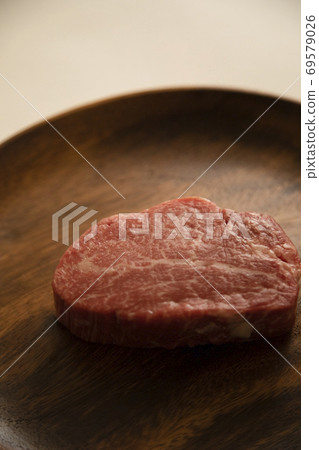 Raw thick fillet steak on a wooden plate Raw thick fillet steak on a wooden plate 69579026