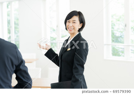 A middle-aged woman in a suit guiding the facility A middle-aged woman in a suit guiding the facility 69579390