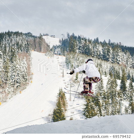 Male skier making jump while skiing in mountains. 69579432