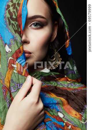 closeup portrait of beautiful young woman in color veil and jewelry 69579999