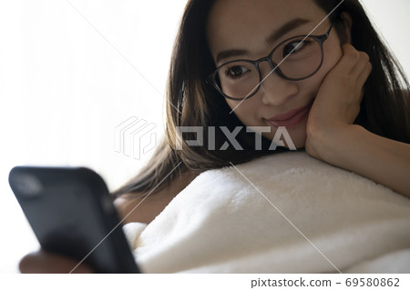 A woman watching a smartphone A woman watching a smartphone 69580862