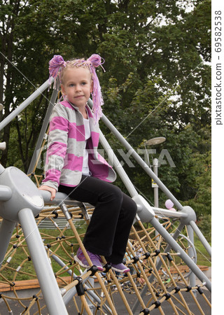 Portrait of a girl on a street Playground. A beautiful girl looks at the camera. Portrait of a girl on a street Playground. A beautiful girl looks at the camera. 69582538