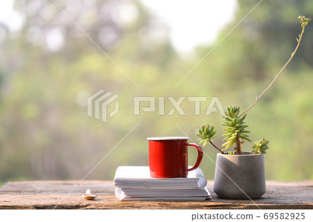 Red coffee cup with notebooks and pencil and clay gray plant pot  69582925