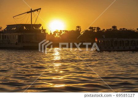 Sun setting over the Nile River in Luxor with silhouettes of ferry boats 69585127