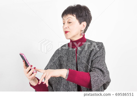 Senior buisness woman standing isolated on grey studio background Senior buisness woman standing isolated on grey studio background 69586551
