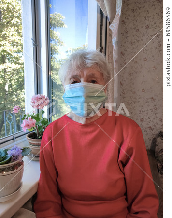 The Covid-19, health, safety and pandemic concept - senior old lonely woman sitting near the window 69586569