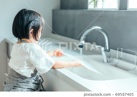 A girl is washing a cutting board in a beautiful kitchen kitchen girl wash 69587405