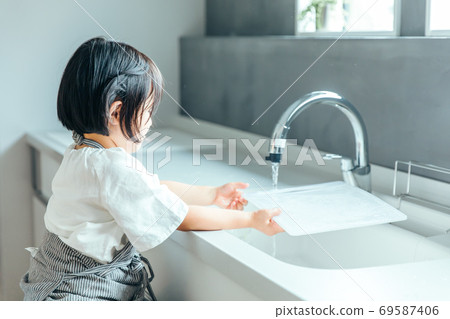 A girl is washing a cutting board in a beautiful kitchen kitchen girl wash 69587406