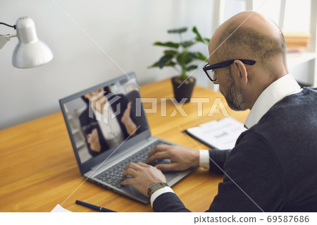 Work online. Senior man working communicates using laptop video chat with partner sitting office at home. 69587686