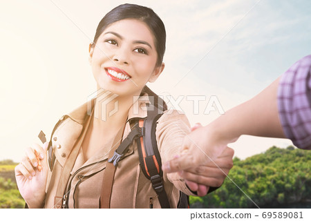 Asian woman with a backpack holding her boyfriend's hand while traveling Asian woman with a backpack holding her boyfriend's hand while traveling 69589081