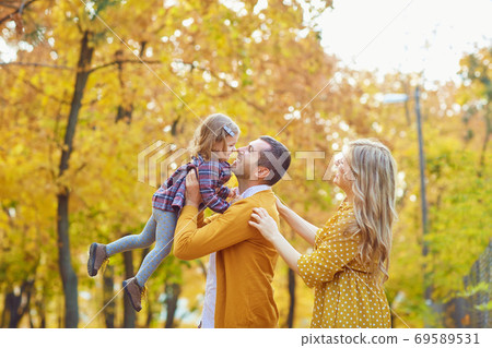 Family playing with baby in yellow park in autumn. 69589531