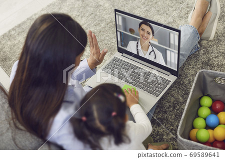 Family doctor online. Mother and baby greet the doctor have a video call laptop to the doctor at home. 69589641