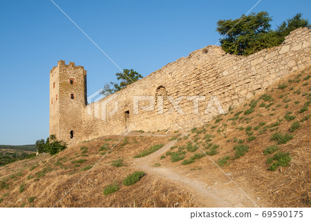 Stone tower of an ancient fortress with adjoining rocky walls Stone tower of an ancient fortress with adjoining rocky walls 69590175