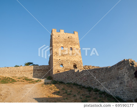 Stone tower of an ancient fortress with adjoining rocky walls Stone tower of an ancient fortress with adjoining rocky walls 69590177