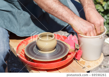Creating clay jar by hands with potter wheel Creating clay jar by hands with potter wheel 69590261