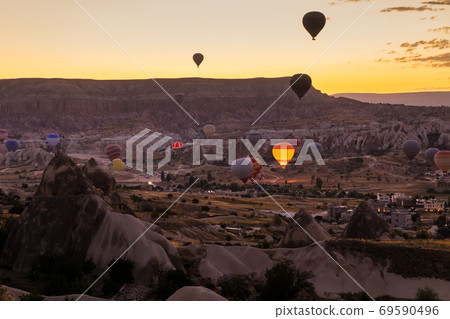 Hot air balloons flying over a volcanic landscape at Cappadocia, Turkey 69590496