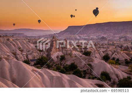 Hot air balloons flying over a volcanic landscape at Cappadocia, Turkey 69590513