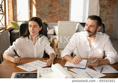 Young family listening to male architect-engineer presents project of future house 69592881