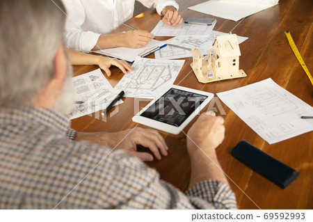Male architect-engineer presents project of future house for young family. Male architect-engineer presents project of future house for young family. 69592993