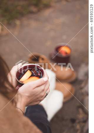 Spicy mulled wine with orange, apples, cinnamon and anise in woman's hands Spicy mulled wine with orange, apples, cinnamon and anise in woman's hands 69593129