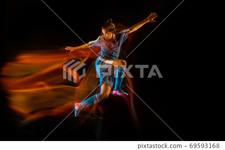 Football or soccer player on black background in mixed light, fire shadows Football or soccer player on black background in mixed light, fire shadows 69593168