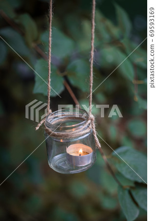 Homemade candle holder hanging on the tree branch, selective focus Homemade candle holder hanging on the tree branch, selective focus 69593169
