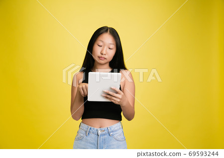 Portrait of young asian girl isolated on yellow studio background 69593244