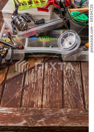 Different fishing tacles with rod and reels on wooden brown background. Different fishing tacles with rod and reels on wooden brown background. 69594726