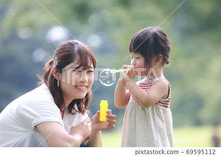 Parents and children playing with soap bubbles 69595112