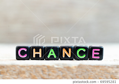 Black bead with color letter in word chance on wood background 69595281
