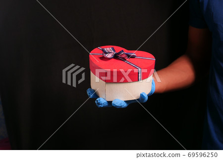 male hand in a blue medical glove gives a gift. isolated in black male hand in a blue medical glove gives a gift. isolated in black 69596250
