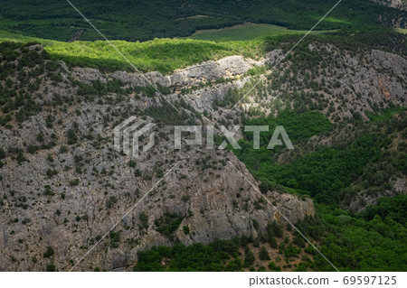Mountains covered by a young green forest in cloudy weather in spring. Mountains covered by a young green forest in cloudy weather in spring. 69597125